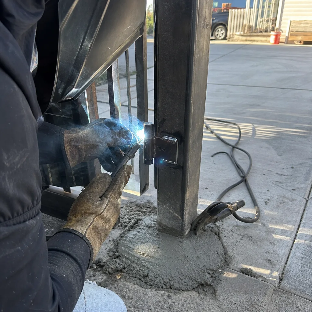 Professional metalworker welding a new hinge onto a metal gate